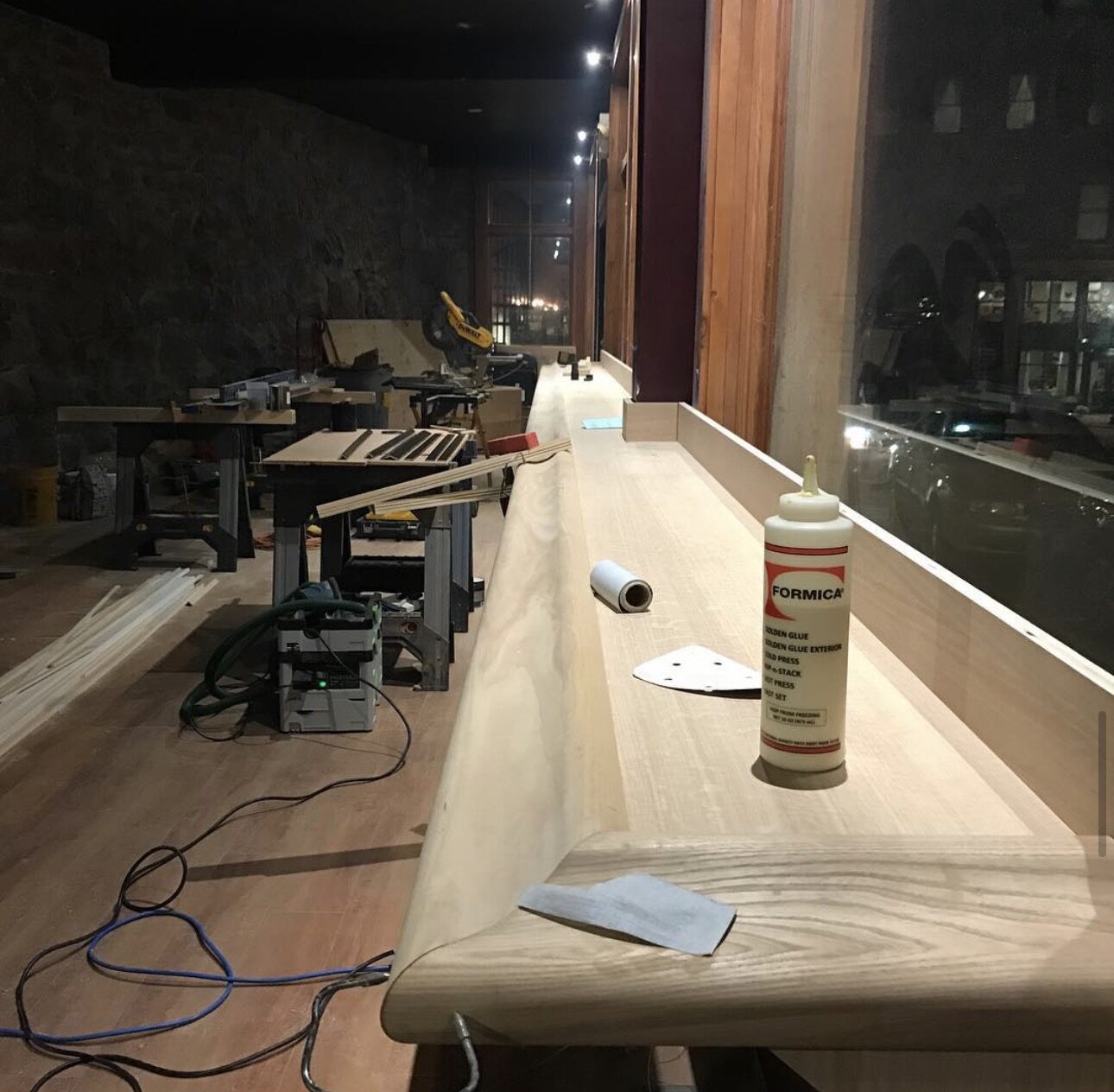 A solid ash bar top being hand-sanded and edge-banded on site