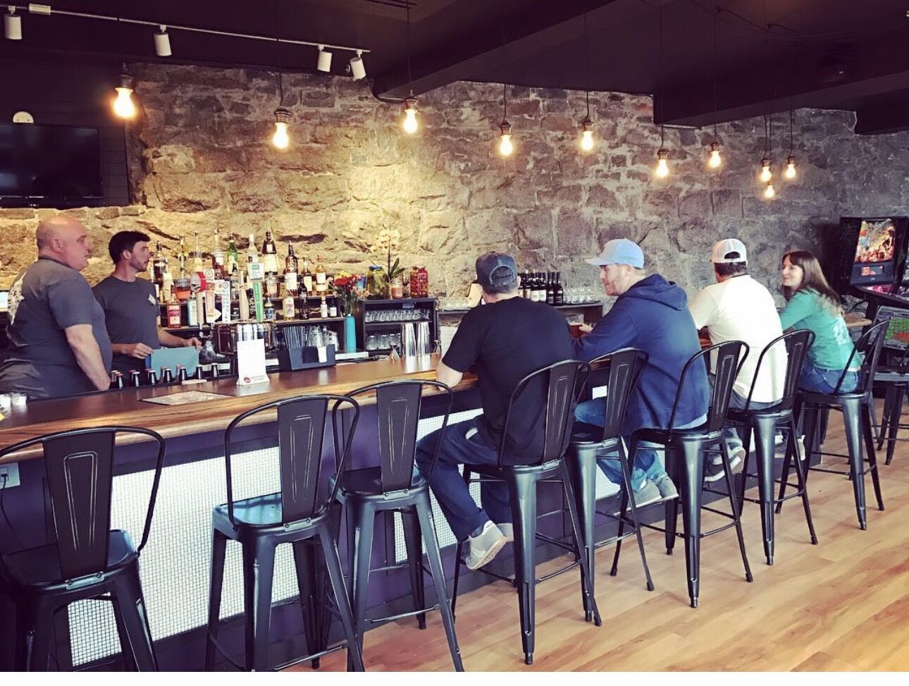 The finished bar at Flip Side Pinball Bar in Westerly, RI, with a hand-built bar top and stone accent wall