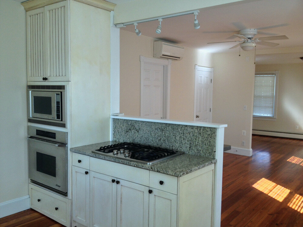 Built-in double wall ovens and microwave in custom cream cabinetry with granite countertop and cooktop